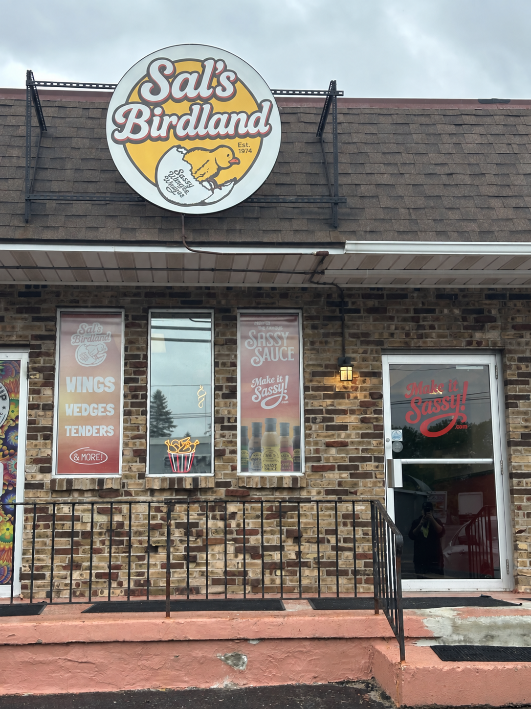 A Sal's Birdland restaurant storefront with the circular logo sign and Sassy Sauce window posters