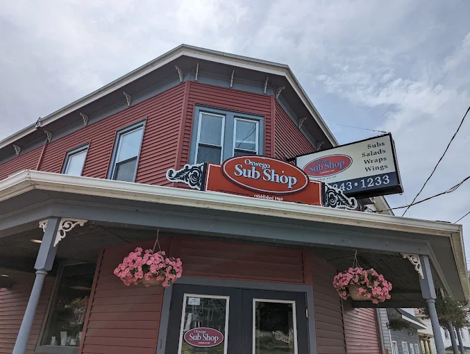 Oswego Sub Shop storefront with hanging flower baskets and its oval sign, now featuring Sal's Birdland
