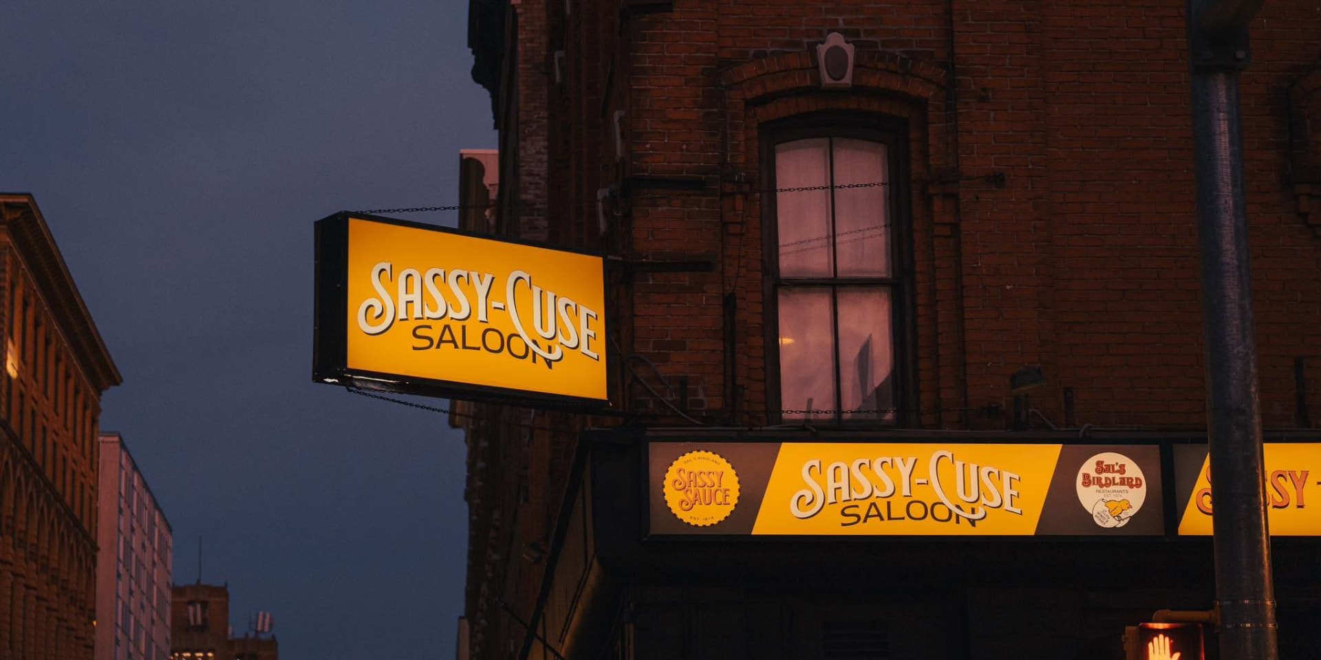 Sassy-Cuse Saloon storefront and illuminated sign on West Fayette Street in Syracuse, New York